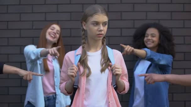 Lachen klasgenoten wijzende vingers op vrouwelijke leerling met schooltas, pesten - Video