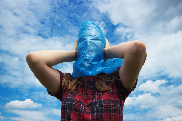 Blauwe plastic zak op menselijk hoofd, concept van grote ecologie probleem. Milieuvervuiling is een van de ernstigste problemen. Zeg nee tegen plastic en Red de aarde. - Foto, afbeelding