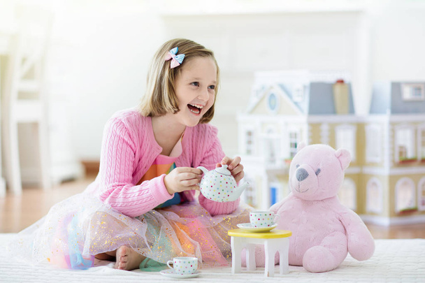 Ένα κοριτσάκι που παίζει με το κουκλόσπιτο. Παιδί με παιχνίδια - Φωτογραφία, εικόνα