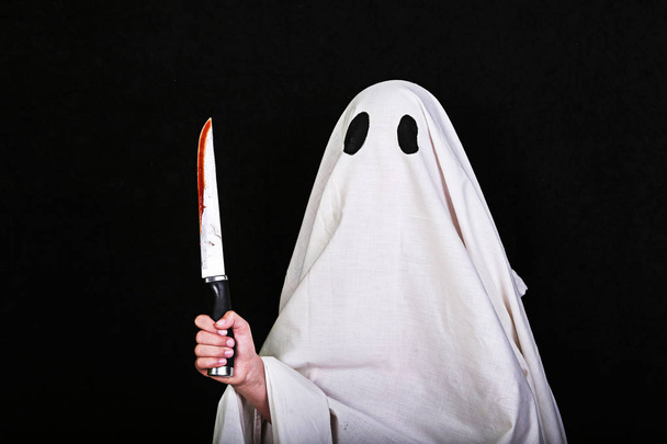 Fantasma Blanco con un cuchillo en sangre sobre fondo negro. Fiesta de Halloween
.  - Foto, imagen