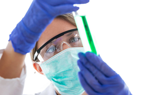 Young scientist woman with protective glasses looking test tube on white background. - Фото, зображення