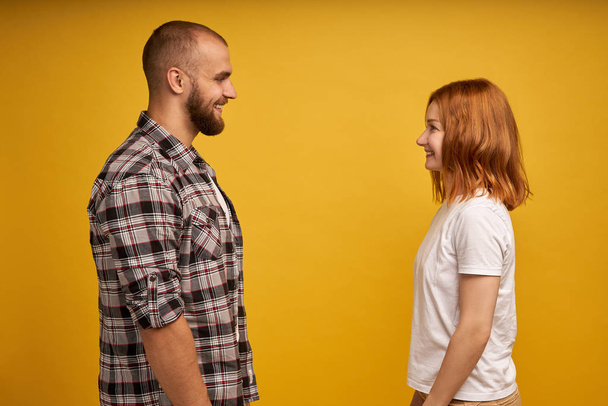 Profile side view portrait of nice lovely charming attractive cheerful flirty couple looking at each other talk conversation connection soulmate isolated over yellow background - Foto, Bild