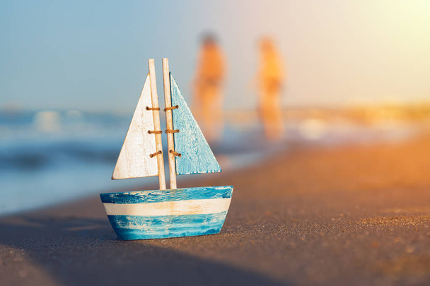 ξύλινο ιστιοφόρο παιχνίδι στέκεται στην άμμο κοντά στην παραλία - Φωτογραφία, εικόνα