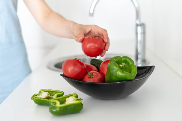 Donna che tiene il pomodoro sopra boccia con verdure a cucina
 - Foto, immagini