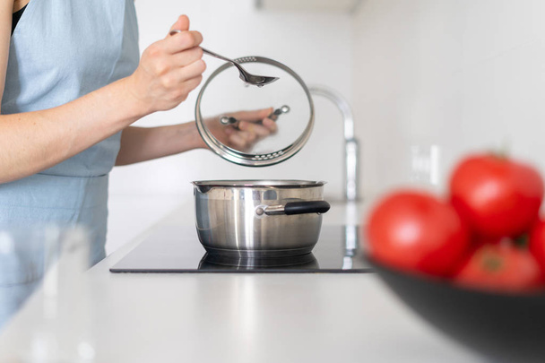 Femme cuisson des aliments dans une casserole, en utilisant intégré dans la cuisinière électrique
 - Photo, image