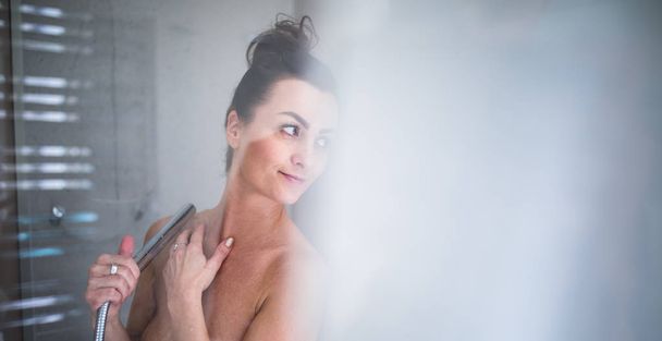 Woman taking a long hot shower washing her hair - 写真・画像