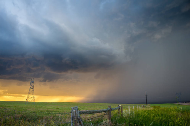 Uma tempestade lança uma torrente de chuva sobre o campo rural ao pôr do sol
. - Foto, Imagem