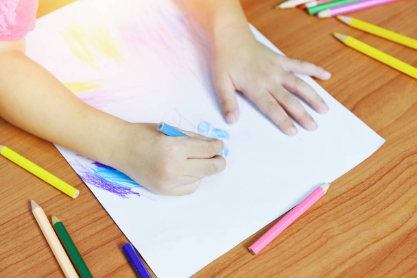 Mädchen malen auf Papierbogen mit Buntstiften auf dem hölzernen T - Foto, Bild