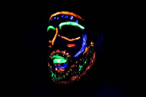 Man met neon make-up voor een neon feestje - Foto, afbeelding