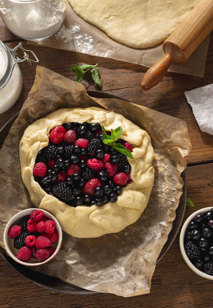 Raw pie cake with fruit strawberry, blueberry, blackberry and raspberry on a wooden table top view - Zdjęcie, obraz
