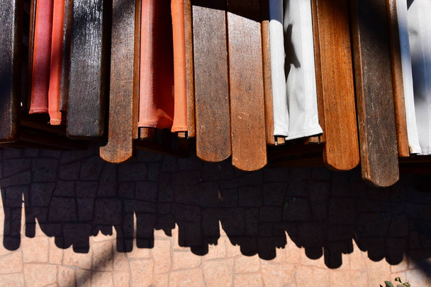 close up view of folding chairs at a restaurant. A minimilistic presentation with the shadow created on the floor below. wooden handles of the chairs are of color brown and the whole image is extraordinary minimalistic capture for photography lovers - Photo, Image