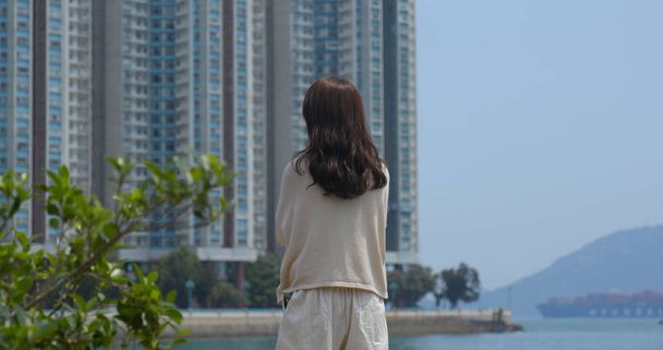 Жінка насолоджується видом на море з фоном будівлі
  - Фото, зображення