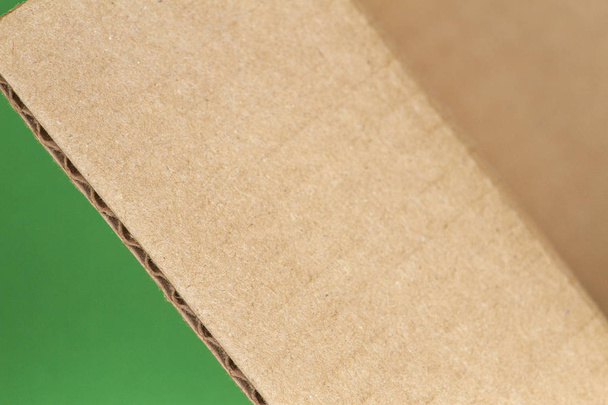 Cierre del borde abierto de la caja de cartón sobre fondo verde
 - Foto, Imagen