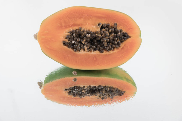 Metà fresca di papaia su sfondo specchio con piena riflessione
 - Foto, immagini
