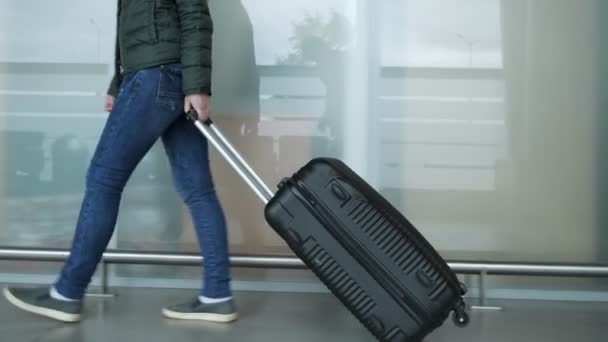 La donna sta camminando nel moderno terminal dell'aeroporto portando valigia, gambe da primo piano
. - Filmati, video