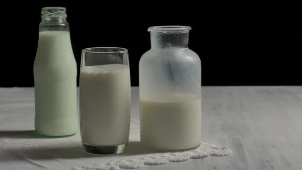 Glas melk en een fles melk op de houten tafel. - Video