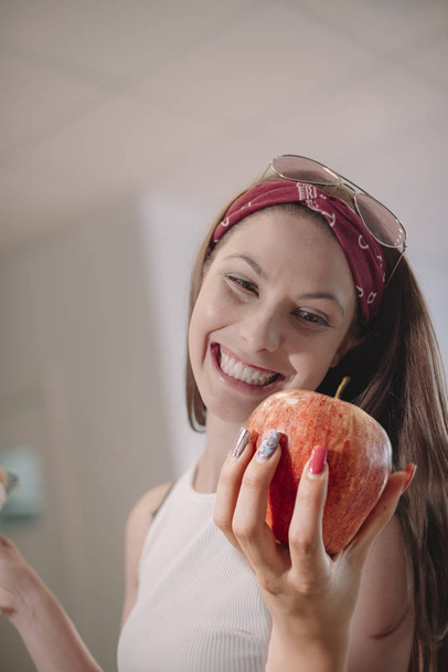 Belle femme modèle heureuse parce qu'elle a une délicieuse pomme rouge - Belle femme avec des lunettes de soleil sur la tête - pomme fraîchement récoltée
 - Photo, image