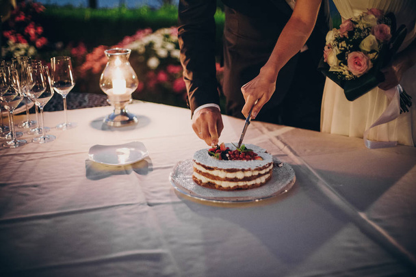 Stylish happy bride and groom cutting together wedding cake with - Valokuva, kuva