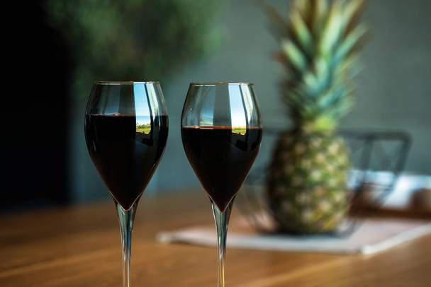Closeup of red wine glasses with blurred pineapple on background, alcohol. - Fotó, kép