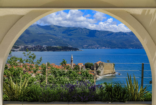 Θέα της παλιάς πόλης της Μπούντβα μέσα από μια αψίδα με την Ακρόπολη και την Αδριατική θάλασσα στο Μαυροβούνιο σε μια ηλιόλουστη μέρα - Φωτογραφία, εικόνα