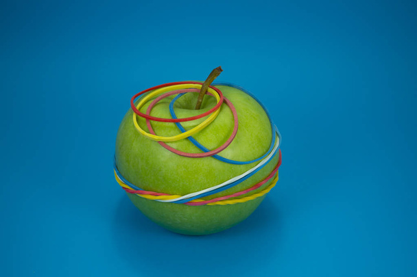 Green apple tied in colorful rubber bands - Photo, Image