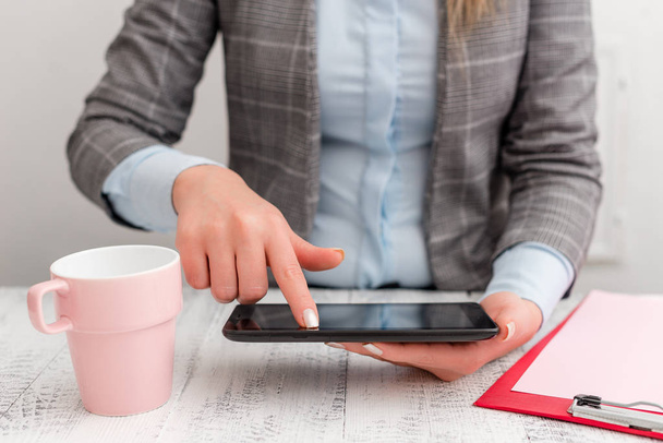 Business woman sitting with mobile phone and cup of coffee on the table. Business concept with office with cup of coffee on the table. - Photo, Image