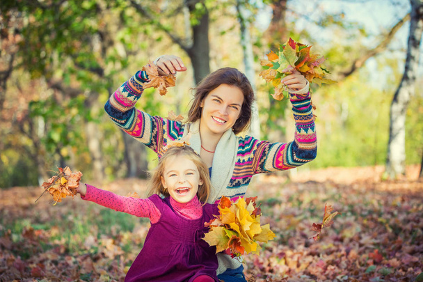Mother and daughter playing in autumn park - Foto, immagini