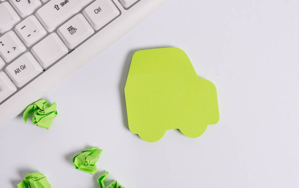 PC-Tastatur mit leerem Notizpapier für Textnachrichten. grünes leeres Zettelpapier in der Form des Autos. Kopierraum auf dem grünen Zettel. - Foto, Bild
