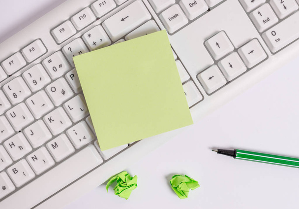 Квадратний порожній зелений папір з олівцем на білому фоні та клавіатурою ПК. Плоский шар над порожнім папером для текстових повідомлень
. - Фото, зображення