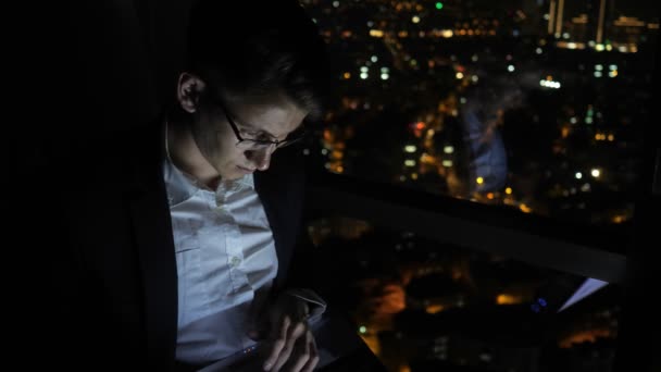 Jeune homme pigiste travaille sur son ordinateur près de la fenêtre à la maison la nuit
. - Séquence, vidéo