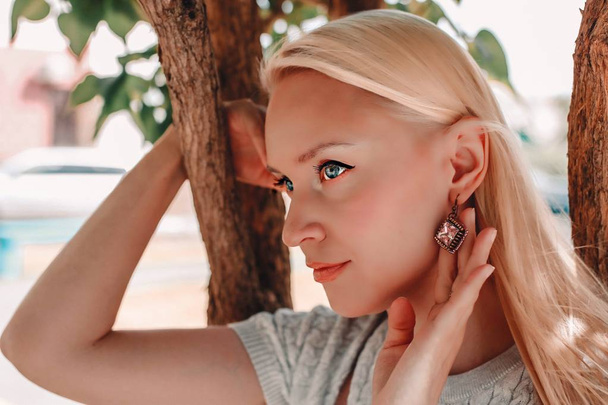 Detail einer jungen blonden Frau, die wunderschöne goldene Luxus-Ohrringe trägt. - Foto, Bild