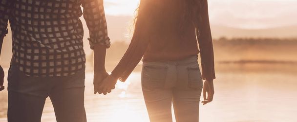 Young loving couple holding hands at sunset - Φωτογραφία, εικόνα