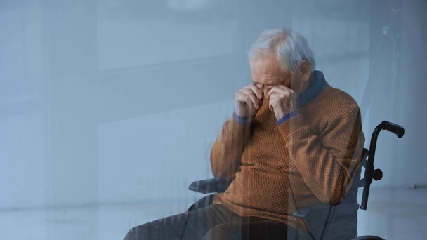 valikoiva painopiste vammaisten vanhempi mies istuu pyörätuolissa ja koskettaa silmiä ikkunan lähellä kaatamalla sade
  - Materiaali, video
