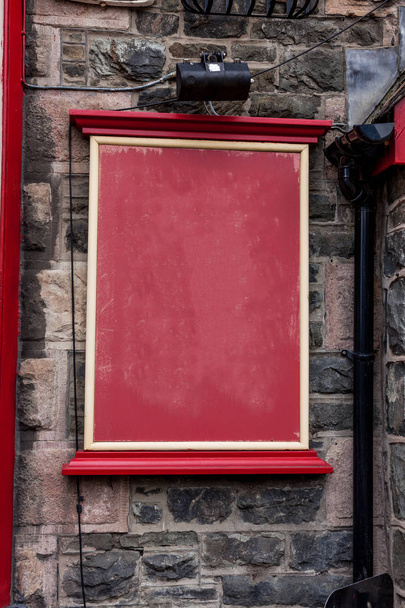 Red empty board with copy space on the wall. Blank ad board for commercial advertising on the old stone wall. Advertising concept with copy space on the red billboard. - Photo, Image