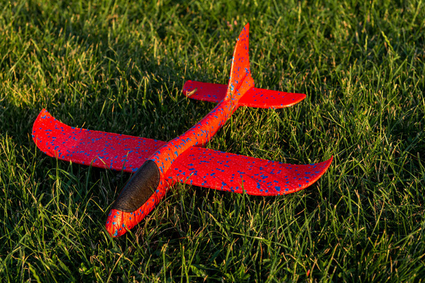 Κόκκινο αεροπλάνο παιχνιδιών ξαπλωμένο στο γρασίδι - Φωτογραφία, εικόνα