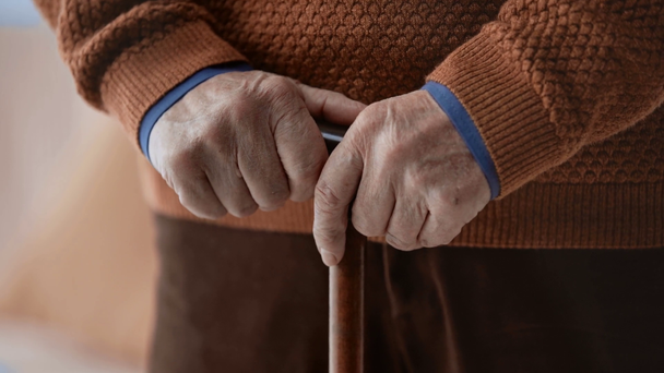 περικομμένη θέα του άρρωστου ανώτερου ανθρώπου Κρατώντας μπαστούνι με χειραψία στο σπίτι  - Πλάνα, βίντεο
