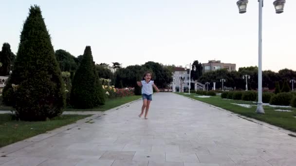 Little funny girls runs towards camera and makes funny things in the park - Filmati, video