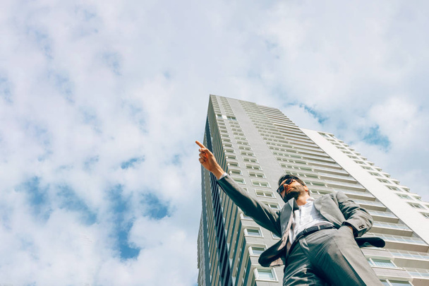 portrait of a businessman seen from below in front of a skyscraper. The sky is the limit. - Photo, Image