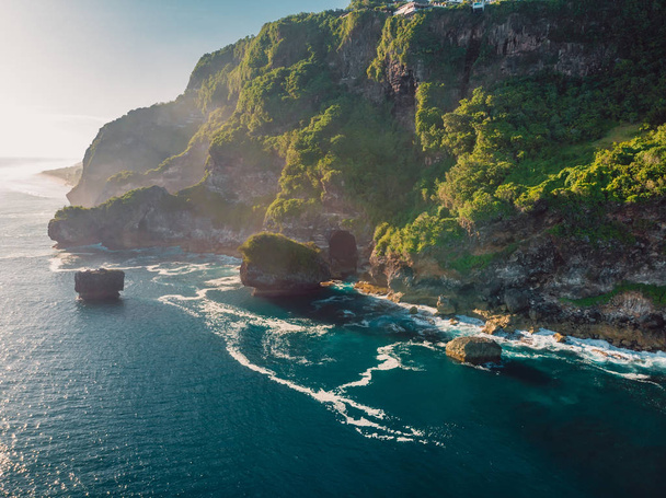 Skalnatý útes a modrý oceán s vlnami na Bali a v krásném světle. Letecký pohled - Fotografie, Obrázek