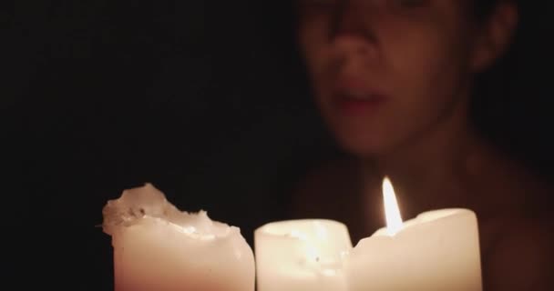 Jeune femme soufflant des bougies sur fond noir. La flamme s'éteint après coup de fille floue méconnaissable disparaît dans l'obscurité. Relaxation réduisant l'énergie de stress
 - Séquence, vidéo