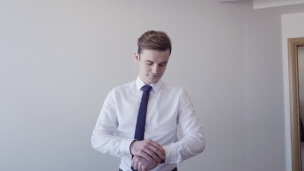 Young businessman adjusts wrist watch and shows thumbs up gesture - Footage, Video