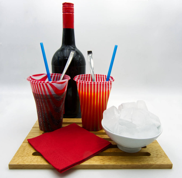 Colorful frozen drinks, bottle, ice cubes, red paper towels, white background  - Fotó, kép