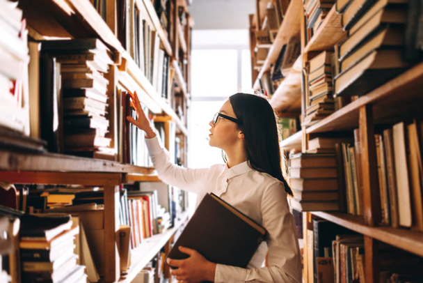 Teenage girl choosing books in library - Valokuva, kuva