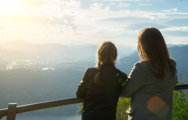 山の頂上から日の出を楽しむ女性とその娘. - 写真・画像