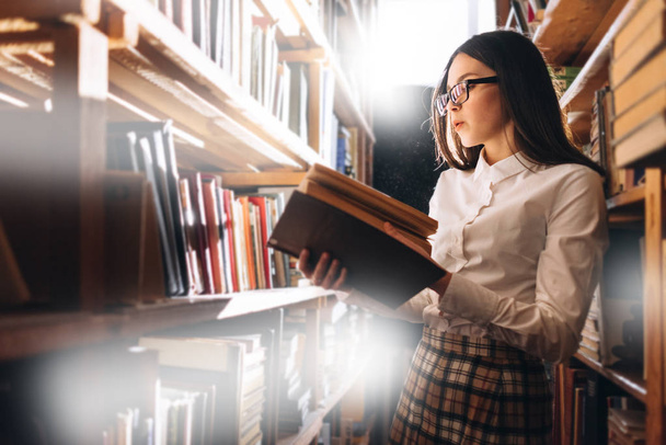 Teen κορίτσι επιλογή βιβλίων στη βιβλιοθήκη - Φωτογραφία, εικόνα