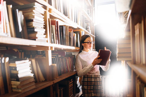 Teenage girl choosing books in library - Foto, imagen