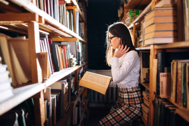 Дівчина-підліток вибирає книги в бібліотеці
 - Фото, зображення