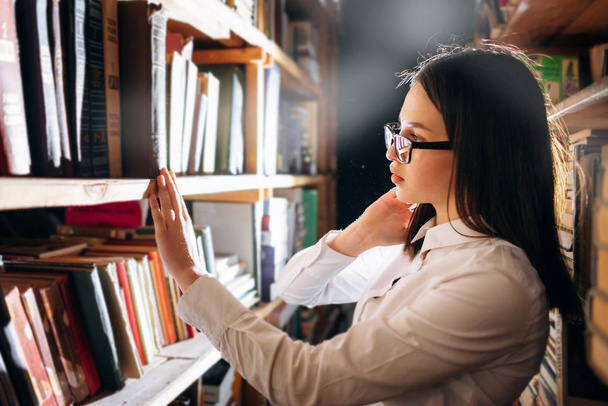 Teenage girl choosing books in library - Photo, image