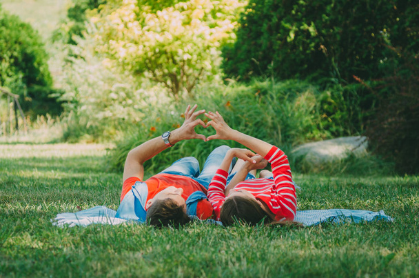 Nuori pari rakastunut makaa ruudullinen puistossa, tehdä kädet s
 - Valokuva, kuva