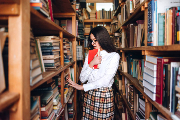 Nastoletnia dziewczyna wybiera książki w bibliotece - Zdjęcie, obraz